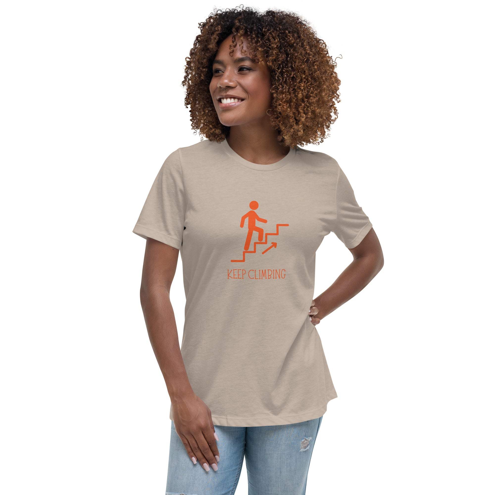 Woman wearing beige Keep Climbing women's t-shirt with motivational graphic and text, paired with blue jeans.