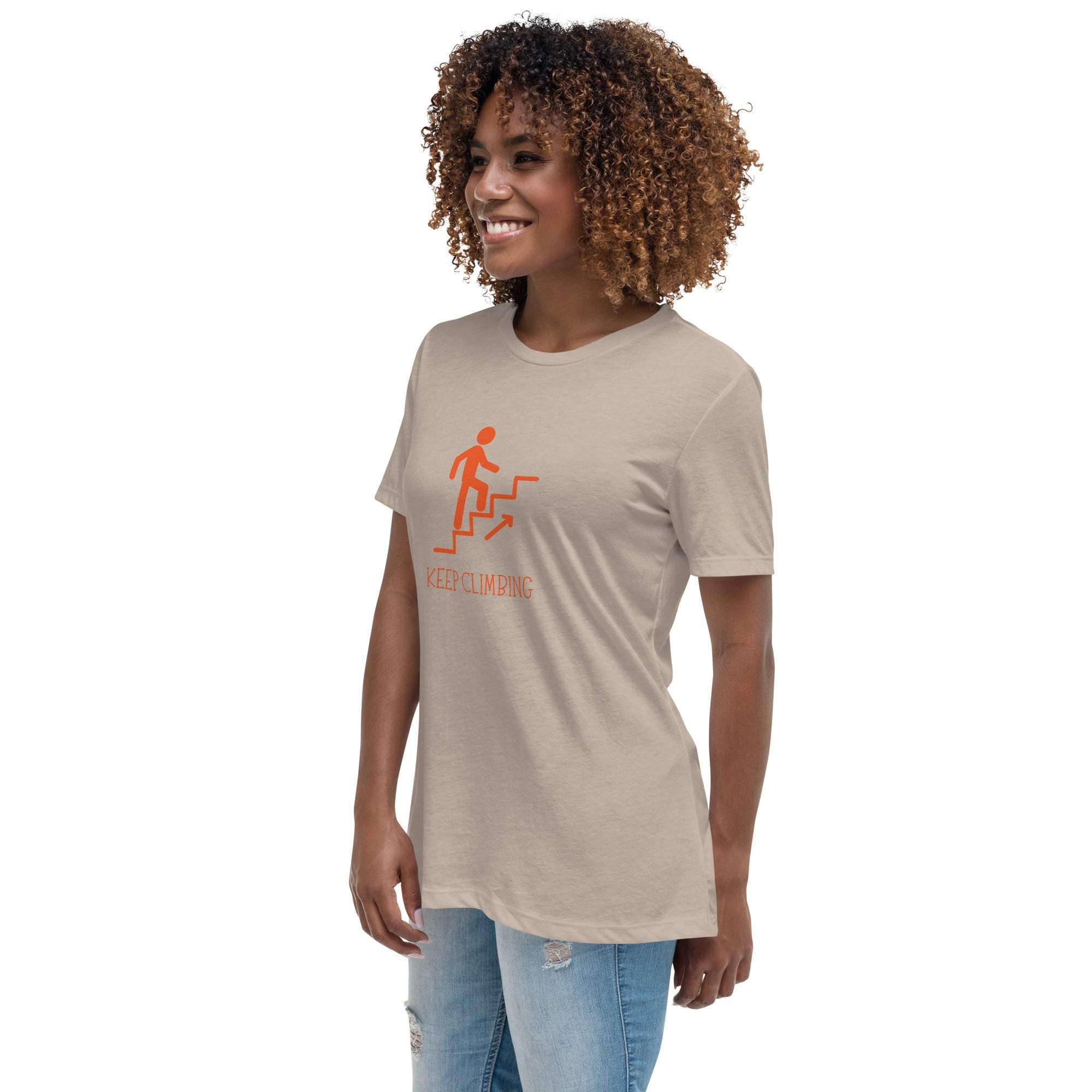 Woman wearing beige Keep Climbing motivational graphic t-shirt with orange print and blue jeans