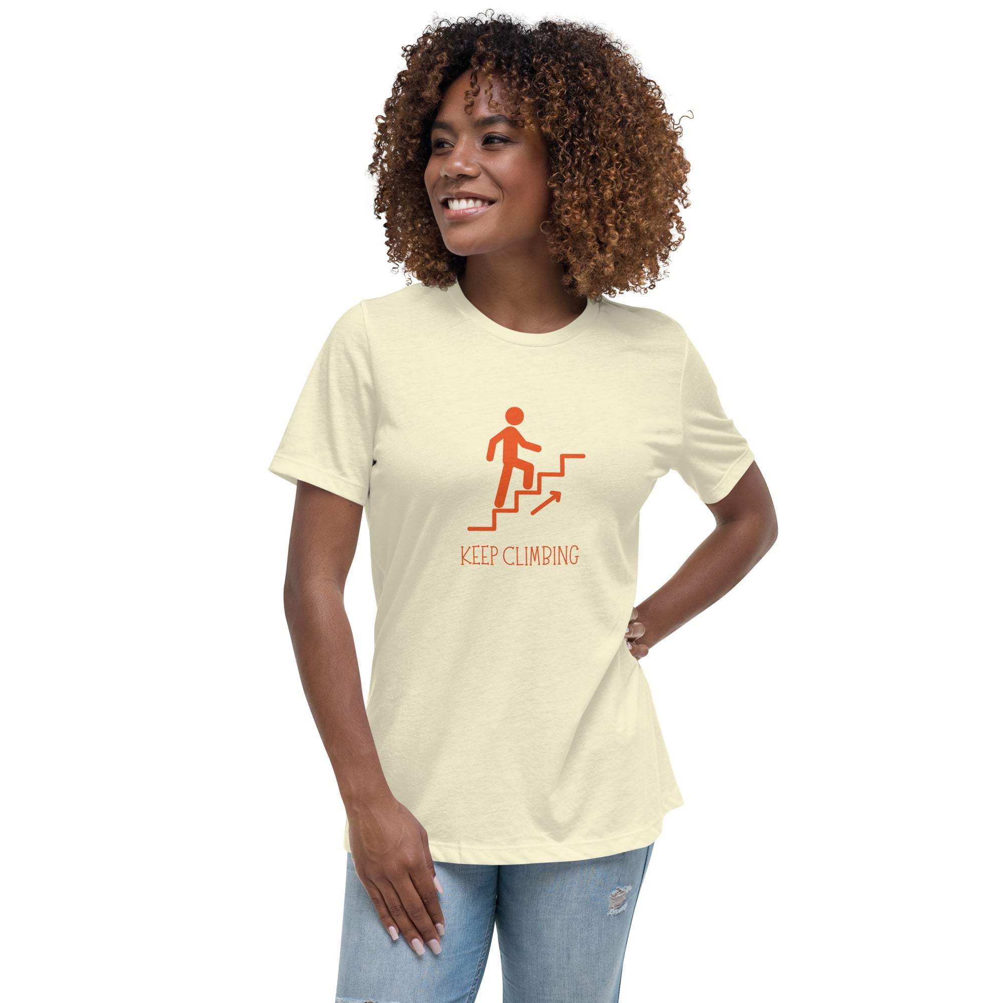 Woman wearing a beige Keep Climbing motivational graphic t-shirt with orange design and casual jeans