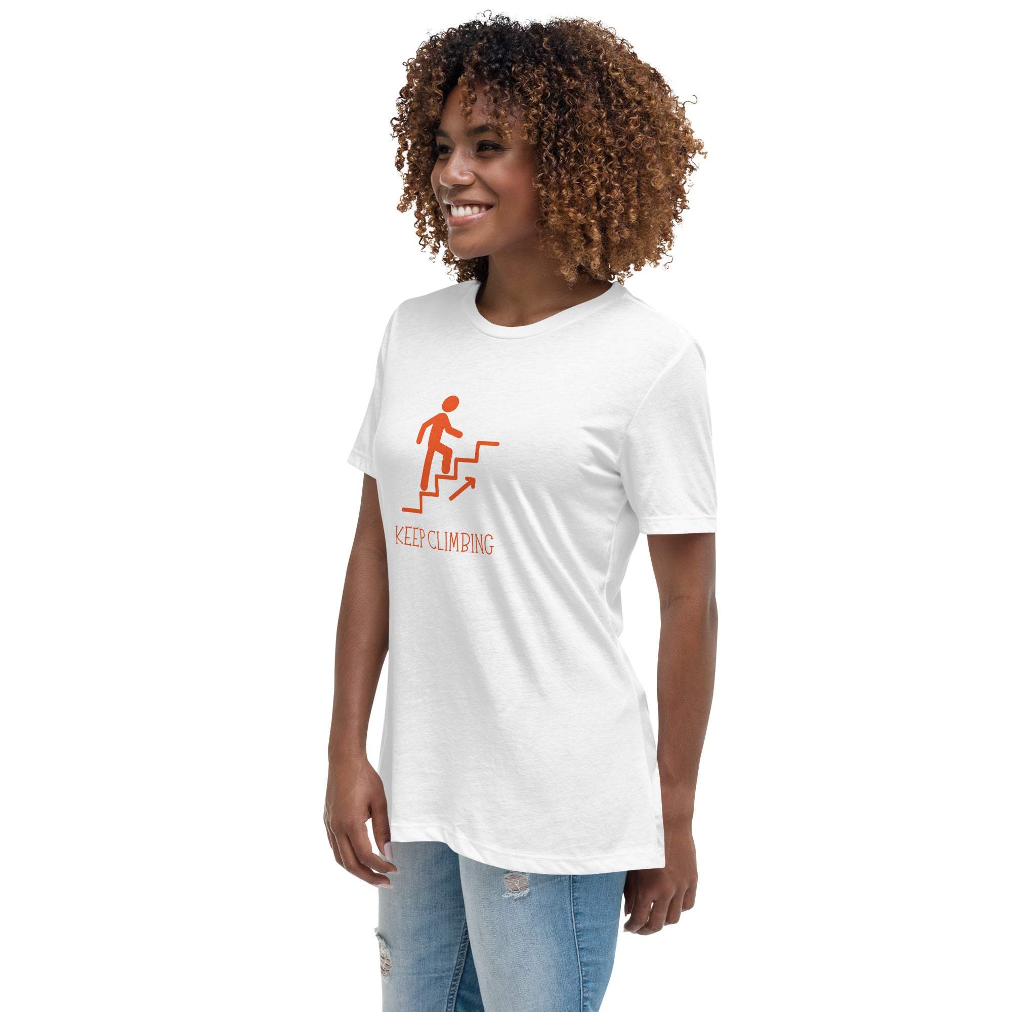 Woman wearing a white Keep Climbing women's t-shirt with orange graphic and text, paired with light ripped jeans
