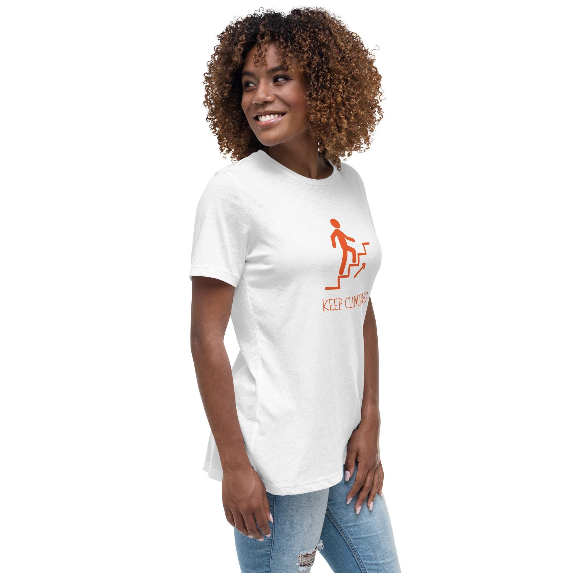 Woman wearing a white "Keep Climbing" motivational graphic t-shirt with orange design and casual jeans.