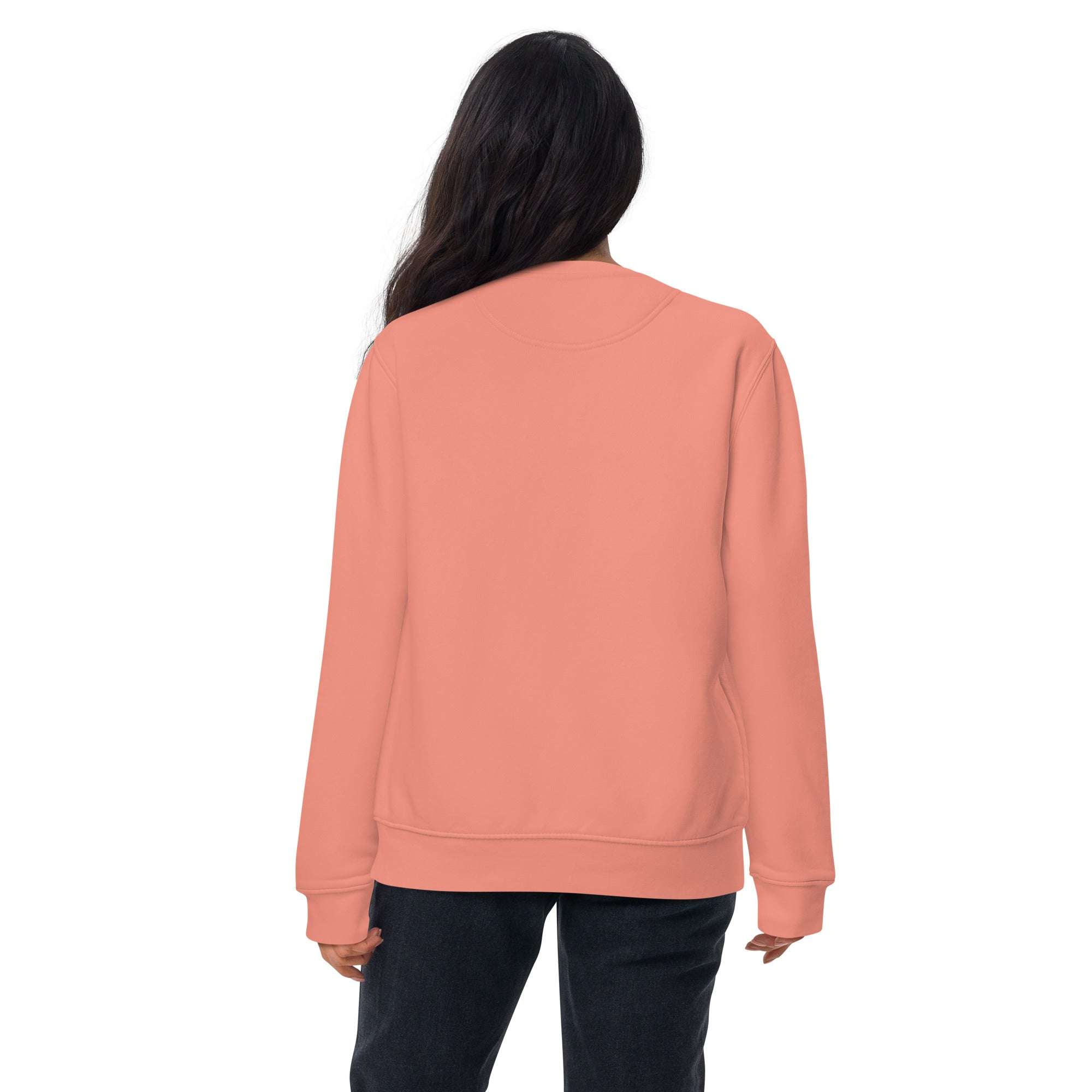Back view of woman wearing coral pink "Just Text Me" sweatshirt, casual unisex crewneck style, paired with black pants