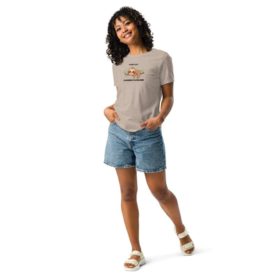 Woman wearing beige "I'm Not Lazy, I Am On Energy Saving Mode" sloth t-shirt with denim shorts and white sandals